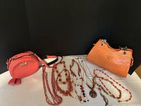 Overall lot showing two orange handbags and six coral-tone necklaces