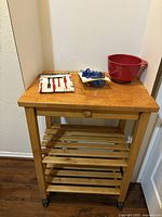 Front view of cart with apron, measuring spoons and bowl placed on top