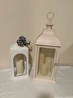 Two white lanterns side by side showing size difference and included candles