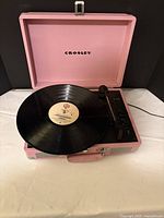 Turntable open with record on platter showing pink case and Crosley logo
