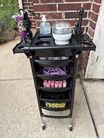 Full view of trolley cart with heat roller set, curling irons and sanitizer on top, drawers partially open