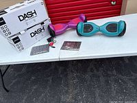 Table with two Jetson Dash boxes, purple and teal hoverboards, charger and packets