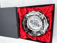 Glass ashtray in red-lined box showing etched RAW logo