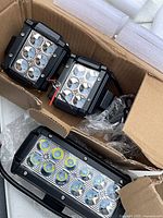 Two square eight-LED lights and one rectangular twelve-LED light bar inside open box