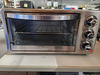 Front view of Oster toaster oven showing glass door, control knobs and interior rack