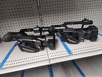 Side profile of both Panasonic camcorders showing controls and viewfinders