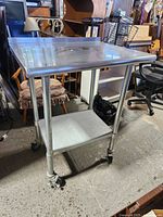 Full view of stainless steel prep table with lower shelf on casters