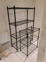 Two black wire shelving units standing in bathroom