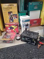 Group shot of boxed Presto heater, pool pump, packaged heat gun, battery charger, tape