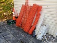 Overall lot showing orange and white fence rolls, cones, bases, green coil
