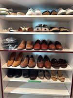 Full shelving unit showing multiple pairs of shoes arranged on five shelves