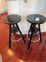 Pair of black wooden adjustable stools side by side