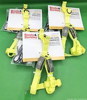 Three packaged yellow LED dog harnesses with tags visible