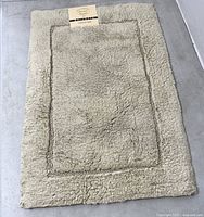 Full view of light green rectangular bathmat showing texture and border