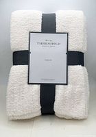 Front view of folded cream throw blanket with Threshold label and ribbon