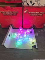 Two boxed LED star toppers and one illuminated showing multicolour mode