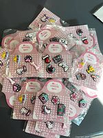 Stack of multiple sealed packs of shoe charms on pink heart patterned cards
