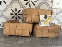 Three tan faux leather woven baskets stacked showing overall appearance and tags attached.