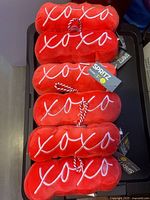 Stack of red plush dog toys showing embroidered "xoxo" and tags
