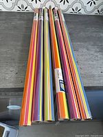 Six colorful striped gift wrap rolls on counter