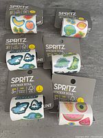 Six packaged Spritz sticker rolls showing the range of shark, dinosaur, fruit and vegetable designs