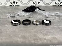Four stainless steel spinner rings laid out with size tags visible