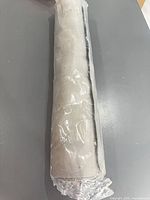 Rolled grey rubber bath mat in plastic wrap, top view