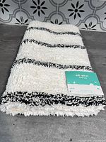 Folded white rug with black stripes and Pillowfort tag visible