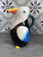 Front view of ceramic toucan pitcher showing overall form and colors