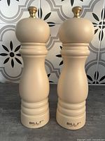 Front view of both cream wooden mills standing upright