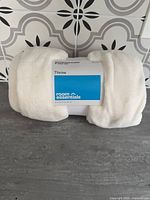 Front view of packaged Room Essentials throw blanket showing brand label