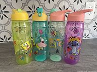Four cartoon-themed plastic water bottles lined up front view