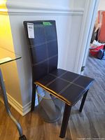 Front angled view of black faux leather side chair showing full shape and stitching