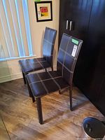 Front angled view of both brown faux leather side chairs