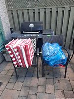two wicker armchairs with stacked cushions in front of grill