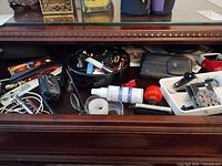 Drawer showing various office supplies, glasses, tape, pens, hearing aid remote