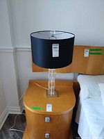 Full view of lamp on bedside table showing shade, lucite column, base