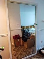 Full front view of large white-framed mirror leaned against wall