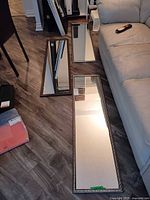 Three rectangular framed mirrors on floor showing size and frame styles