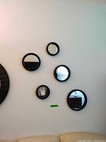 Five black-framed round mirrors mounted on wall