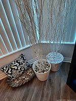 Two faux trees in white pots with stones, stone plate with rocks, patterned pillow