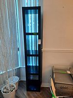 full view of tall black shelving unit beside wall