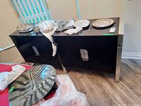 Front and top view of dark wood sideboard with contents on top