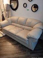 Full front view of cream sofa showing three cushions and armrests