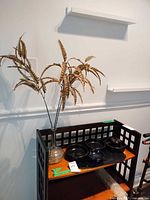 Full view of stand showing vase with faux floral and black ceramic dishes