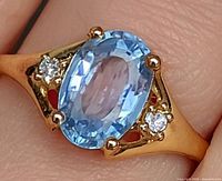 Ring on finger showing sapphire and diamonds