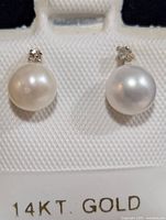 Front view of pearl and diamond stud earrings on card with 14KT GOLD marking