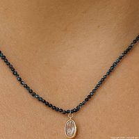 Necklace worn on model showing scale and blue diamond bead strand with pendant
