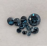 Close view of nine blue diamonds showing color and cut