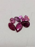 Seven loose faceted rubies on white surface